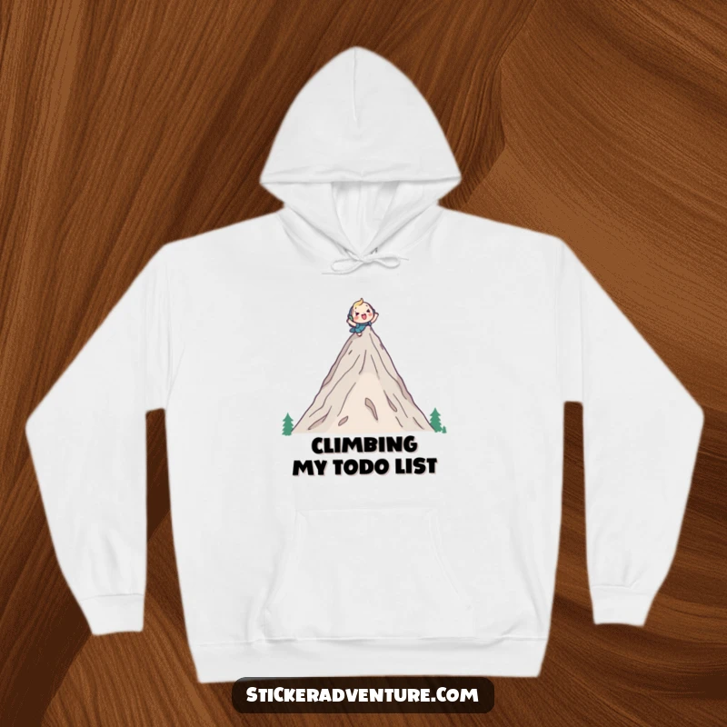 Funny hoodie featuring a cute character cheerfully climbing a tall mountain peak with a backpack, symbolizing achievement and adventurous humor.